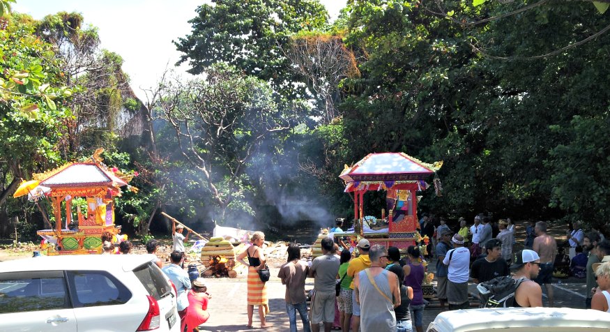 Cremation happening next to the beach at Sanur Bali as tourists look on.