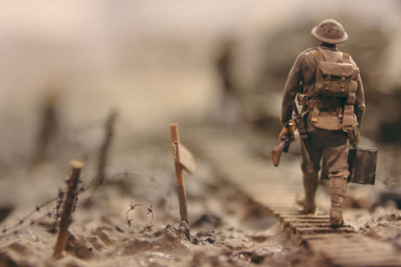 Soldier walking past barbed wire. Photo by Stijn Swinnen at Unsplash