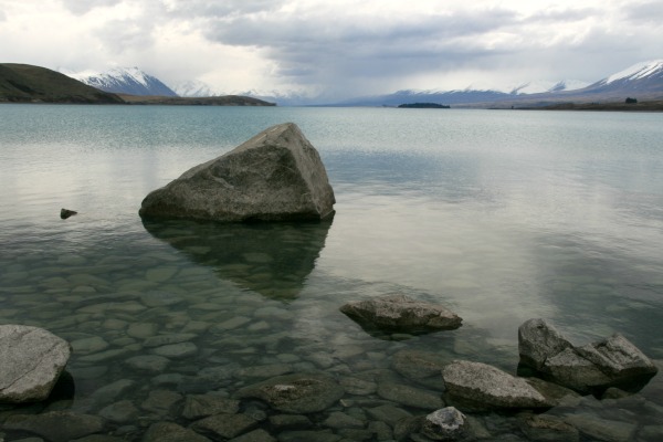 Large Rock in a Lake with Snowcapped Mountains.  Calming view for those coping with dementia